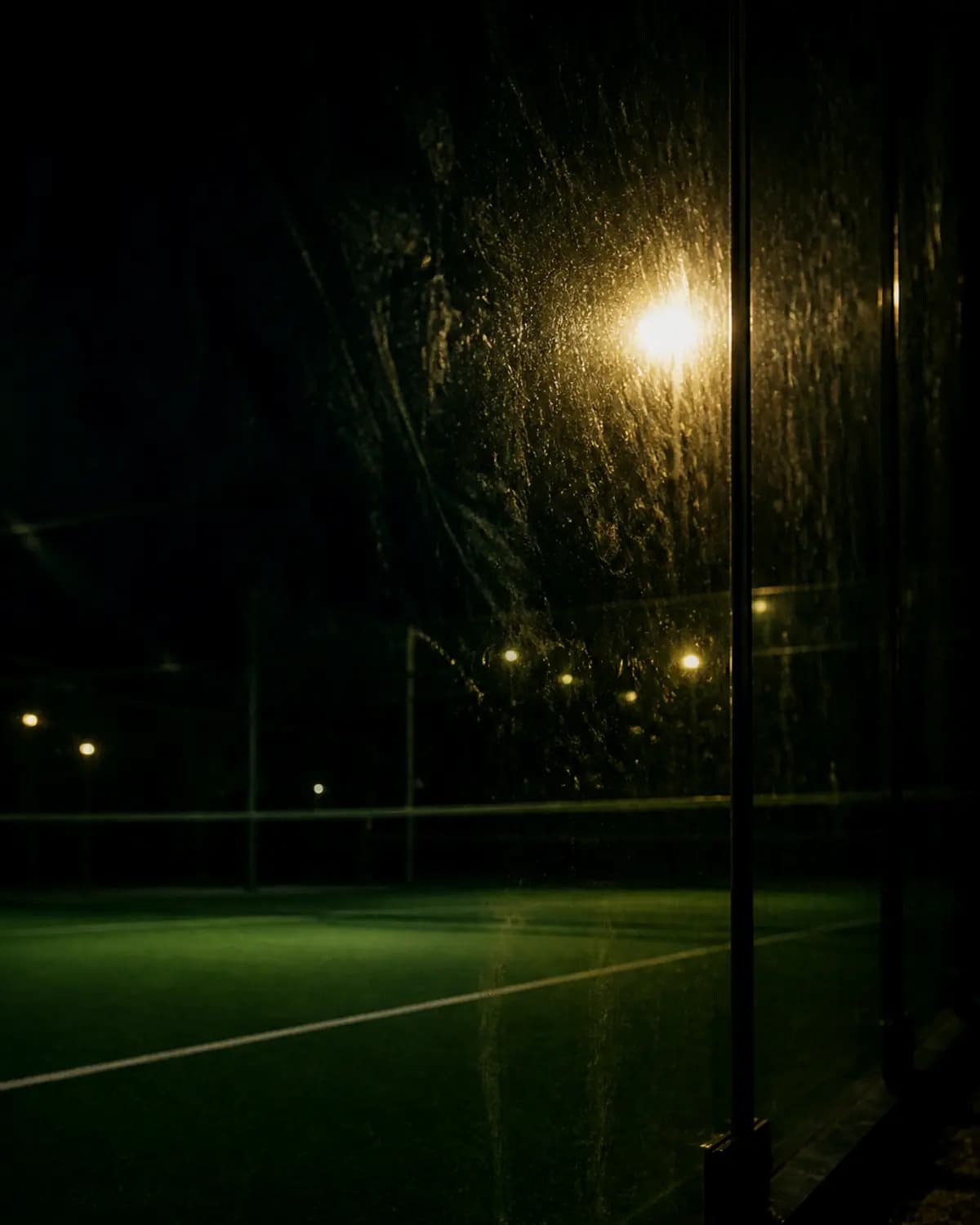 Floodlight refracted through the glass wall of a court